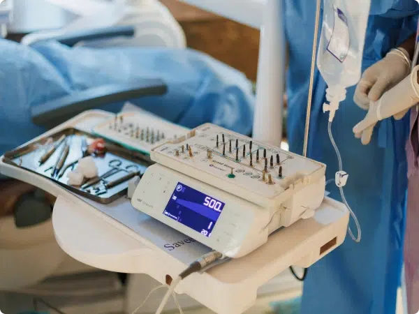 Dental equipment with tools and a digital display, alongside an IV stand in a clinical setting.