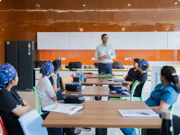 Dr Yohan leading a mentorship session with a group of attentive participants in a modern training room.