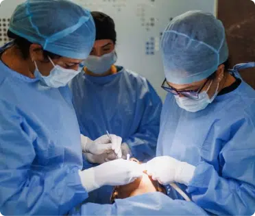 Surgical team in blue scrubs and masks performing a procedure in a medical setting.