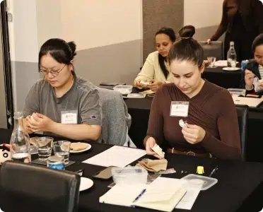 Two women focused on crafting activities at a conference table, with materials and drinks in front of them.